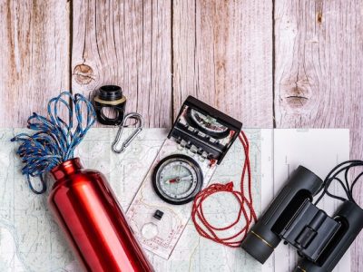 Materiel de randonnee dispose a plat sur une surface en bois : sac a dos, gourde, carte, lampe et vetements