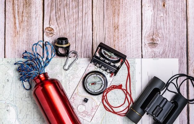 Materiel de randonnee dispose a plat sur une surface en bois : sac a dos, gourde, carte, lampe et vetements